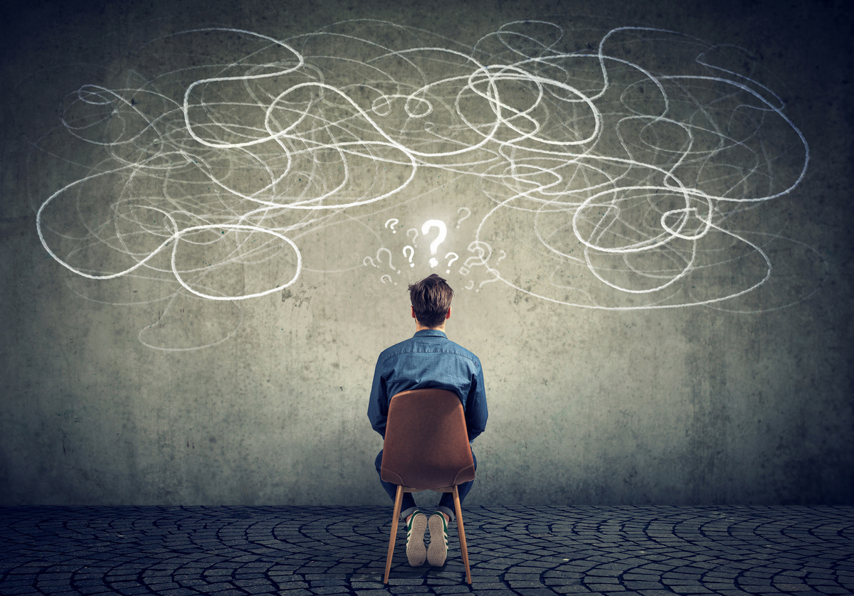 businessman sitting on chair looking at a scribble on a wall feeling confused